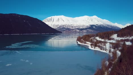 4k drone video of snow covered lakeside mountains in alaska during winter