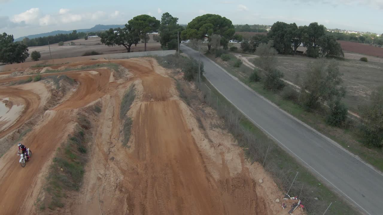 vista aérea oscilante de la pista vacía con el piloto de motocross saltando al costado