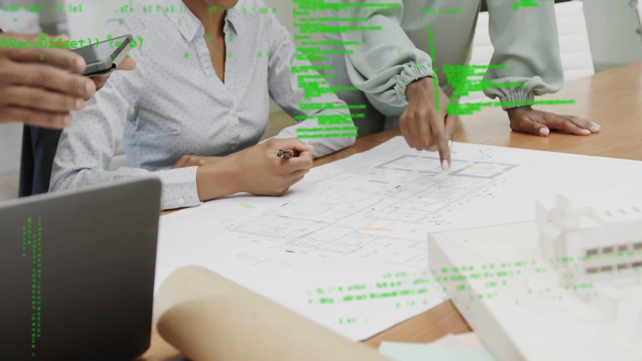 Il responsabile indica, avviando la revisione del design; seduto con una penna che controlla i piani, un tablet mostra una sovrapposizione.