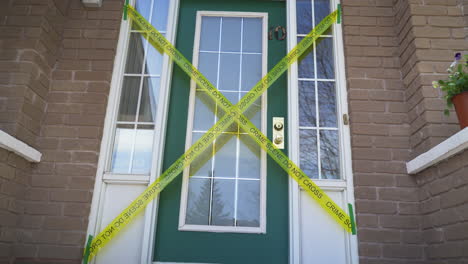 Crime-scene-do-not-cross-yellow-tape-across-front-door-of-house