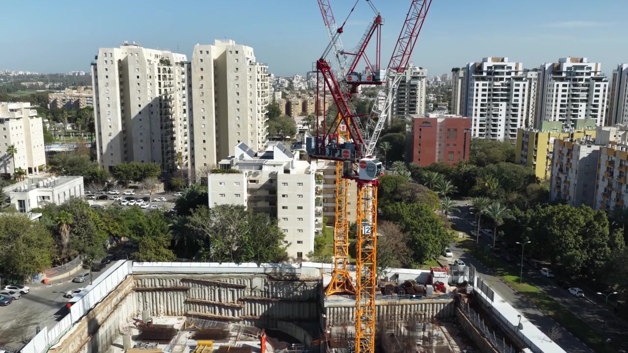 Vista aérea con dron de una importante obra de construcción urbana en el centro de Tel Aviv, con múltiples grúas torre, equipo industrial y el horizonte de la ciudad circundante