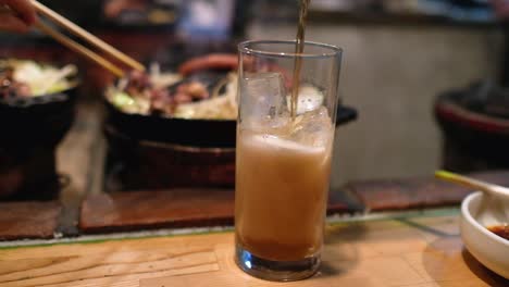 Vertiendo-Cerveza-De-Jengibre-En-Un-Vaso-Lleno-De-Hielo-En-Un-Restaurante-Japonés-Jingisukan