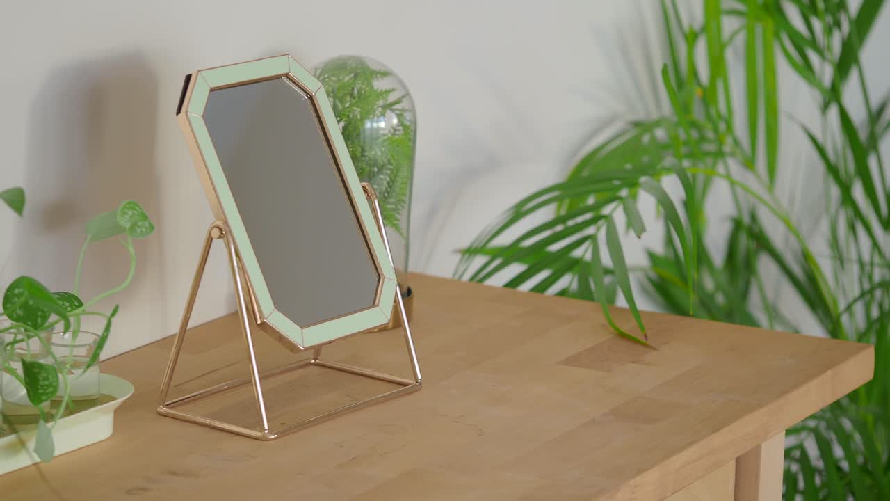 Elegante specchio cosmetico color oro rosa e verde menta su tavolo di legno