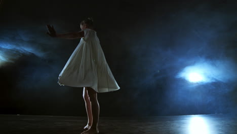 Una-Mujer-Vestida-De-Blanco-Baila-En-El-Escenario-Las-Dramáticas-Danzas-Del-Ballet-Moderno.-Una-Bailarina-De-Ballet-Mueve-Plástico-Realizando-Coreografías-Modernas-En-Humo.