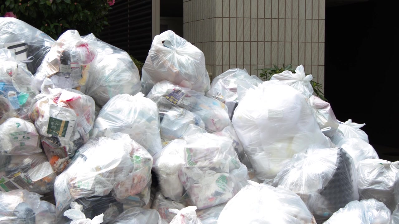 Inquadratura statica di sacchi di rifiuti domestici accumulati su un marciapiede a Tokyo, Giappone