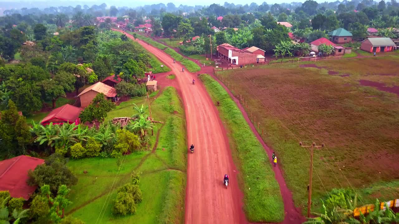 motocicletas conduciendo en una carretera rural en uganda, áfrica - fotografía aérea