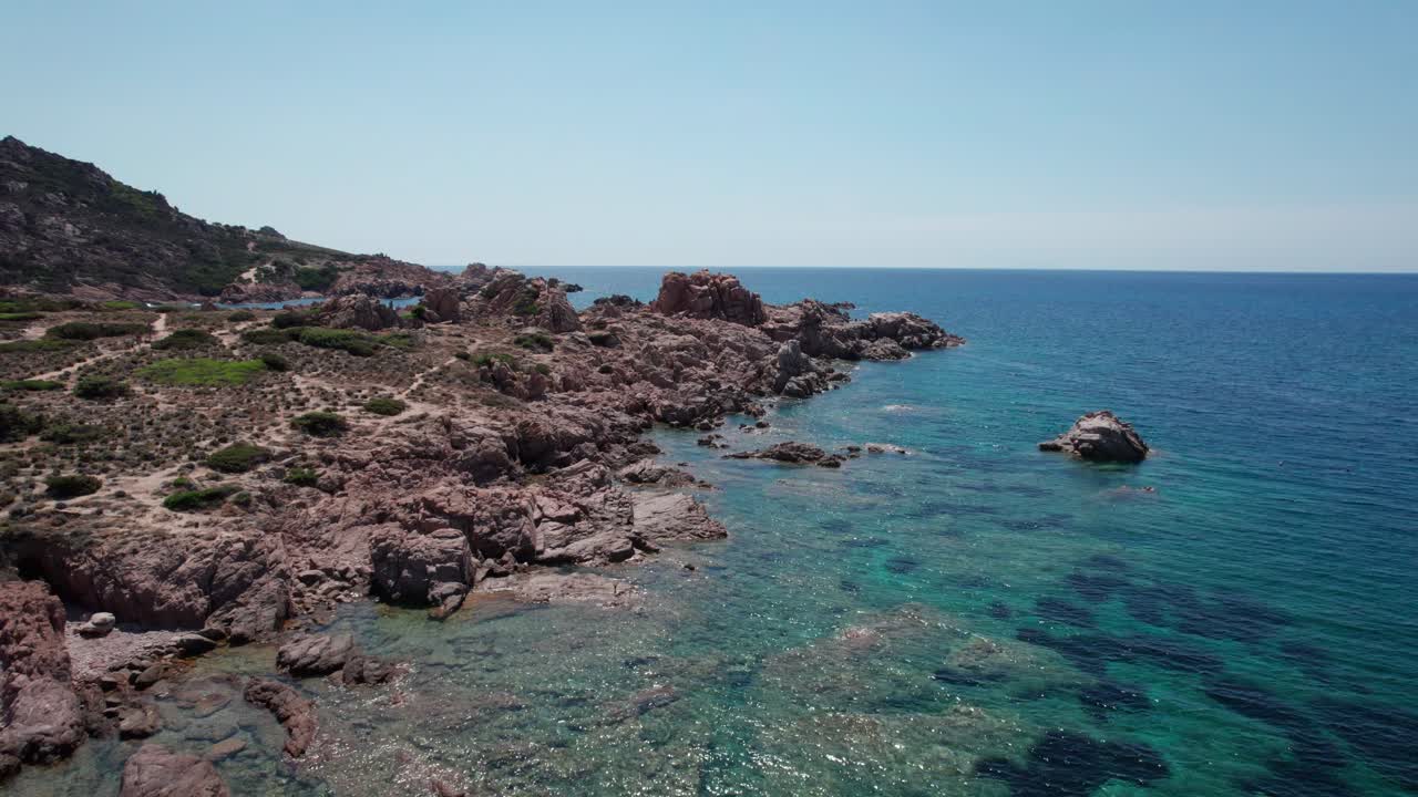 Riprese aeree in movimento, inquadratura con tilt-up sulla costa rocciosa in Sardegna, Italia, durante l'estate, meta di viaggio.