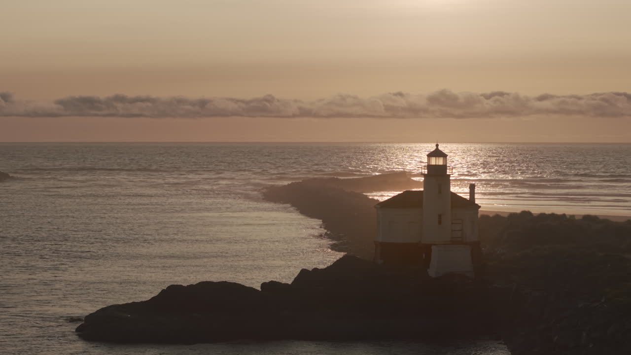 Static drone shot of lighthouse in Bandon Oregon at sunset.