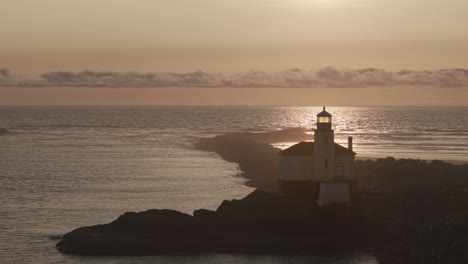 static drone shot of lighthouse in bandon oregon at sunset.