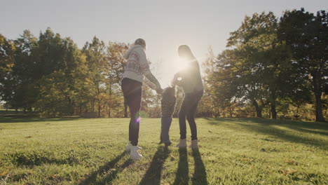 A-mother-with-an-older-daughter-plays-with-her-younger-brother,-leads-him-by-the-hands-and-lifts-him-up.