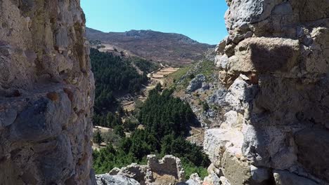 Looking-through-a-gap-in-the-wall-of-the-castle-ruins-of-Paleo-Pili-an-historical-site-on-the-island-of-Kos-in-Greece