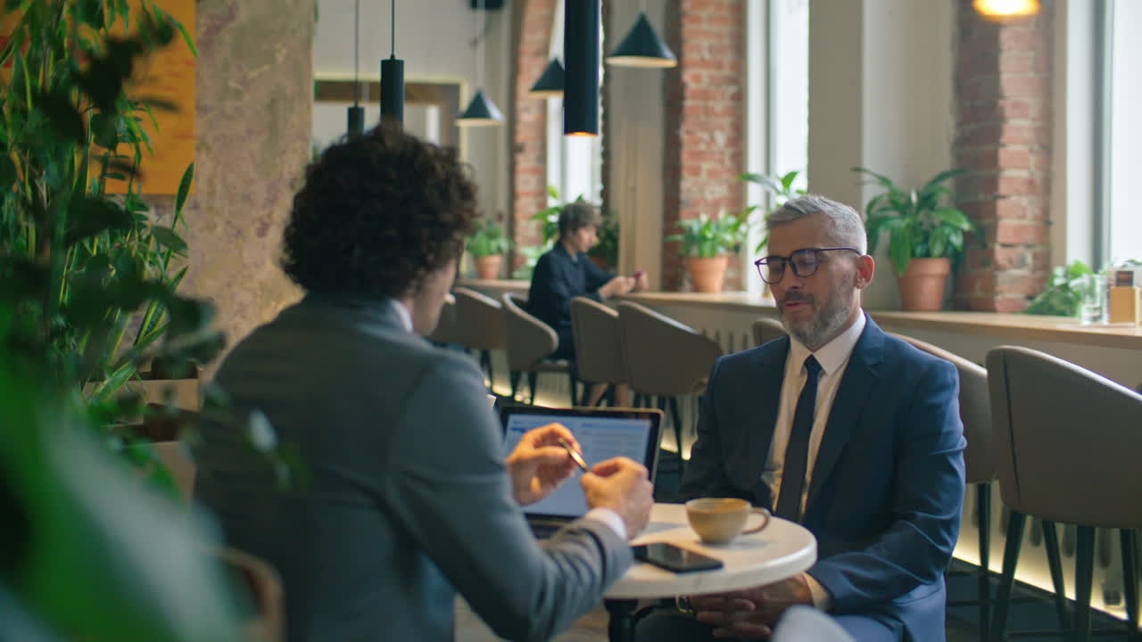 Two Business Partners Having Conversation over Coffee in Modern Cafe