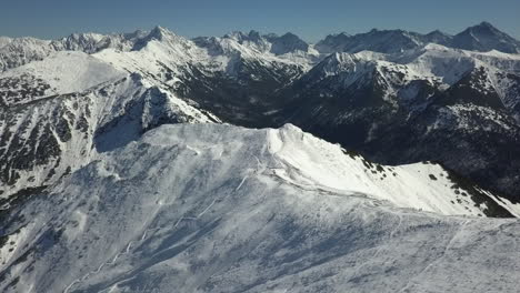 Crisp-winter-mountain-aerial-with-hikers-seen-on-summit-ridge-below