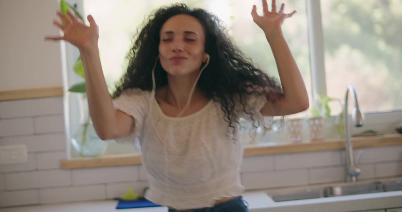 A woman with curly hair dancing alone