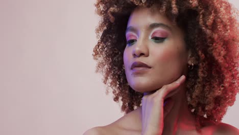 mujer biracial con cabello oscuro en luz azul y rosa con espacio de copia, cámara lenta