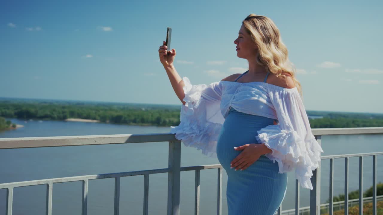 Happy Pregnant Woman Taking Selfie with Smartphone by Scenic River