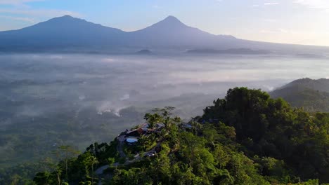 cinematic drone shot of menoreh hill with green landscape and flying clouds in sunlight - central java, indonesia - aerial panoramic establishing shot