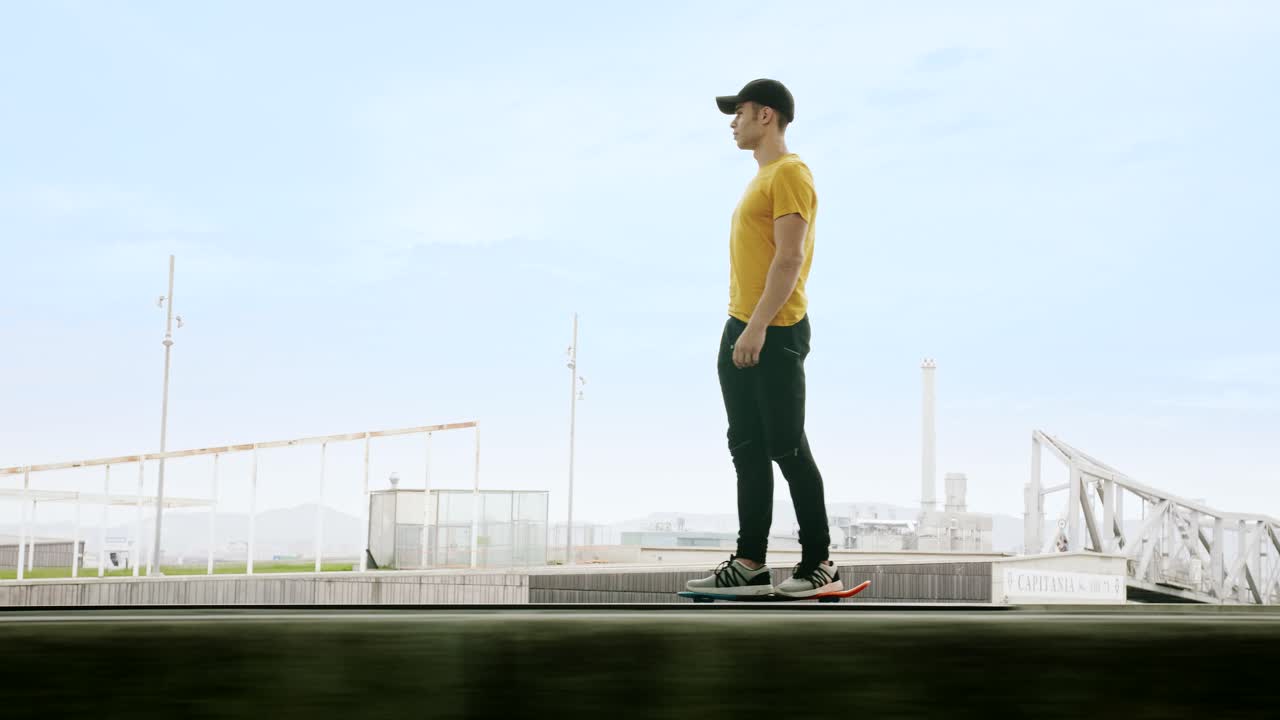 вид сбоку на молодого привлекательного модного мужчину, быстро катающегося на скейтборде под солнечной батареей в утренний солнечный день на фоне городского пейзажа