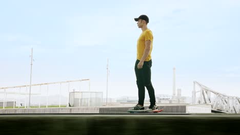 lateral view of a young attractive trendy man skateboarding fast under a solar panel on a morning sunny day with an urban city background