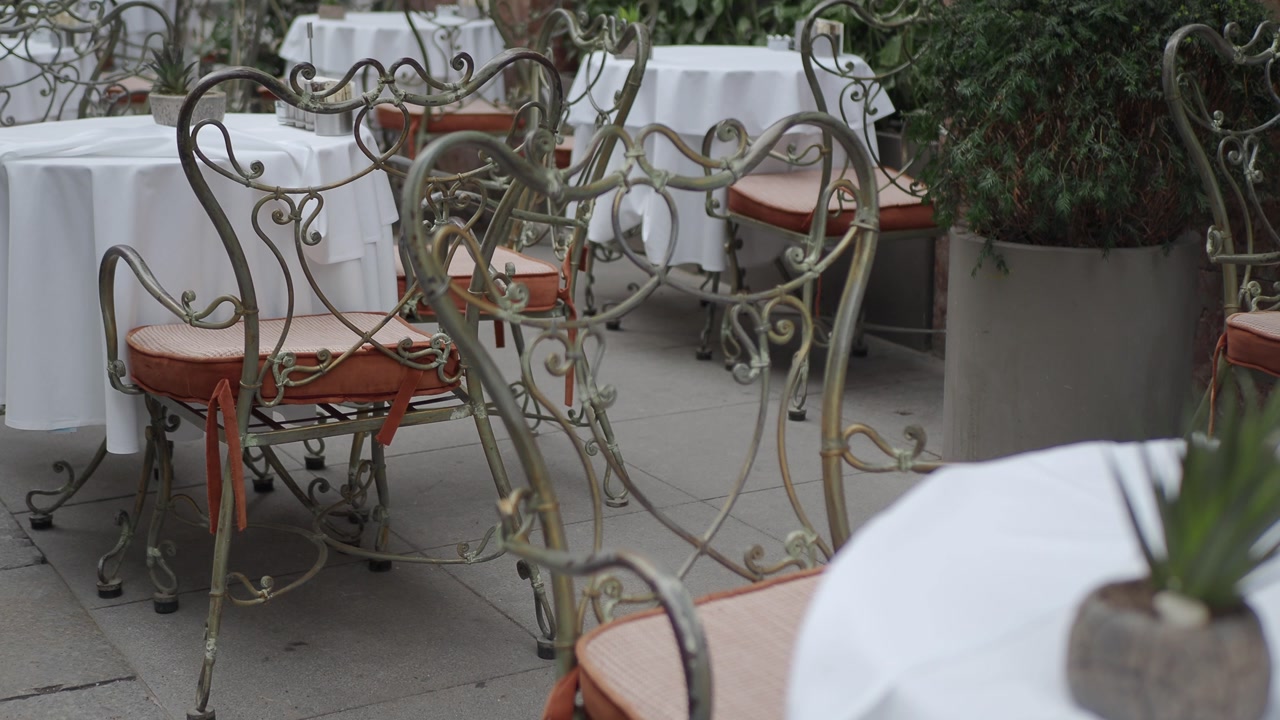 Quiet Outdoor Cafe with White Tables and Ornate Metal Chairs