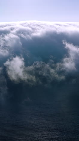 blue ocean water covering with thick fog. bright sun shining on the top of hazy cloudscape. aerial view. vertical video