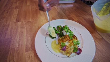 chef caribeño añadiendo crema al bacalao asado en la sartén