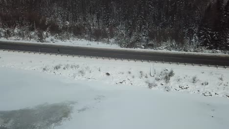 Man-running-on-highway-in-the-winer-in-Canada---Drone-4k-Aerial-Frozen-lake