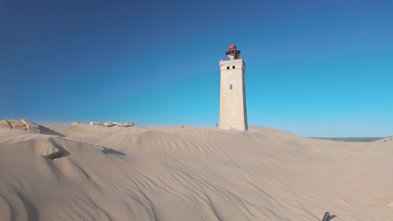 Farol Rubjerg Knude na Dinamarca Isolado em Dunas de Areia sob um Céu Azul Claro em uma Ampla Paisagem Desértica Costeira