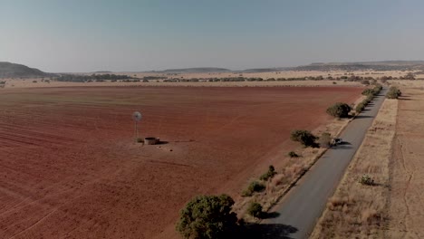 aerial fly over of a working windpump in a dry field with a gravel road