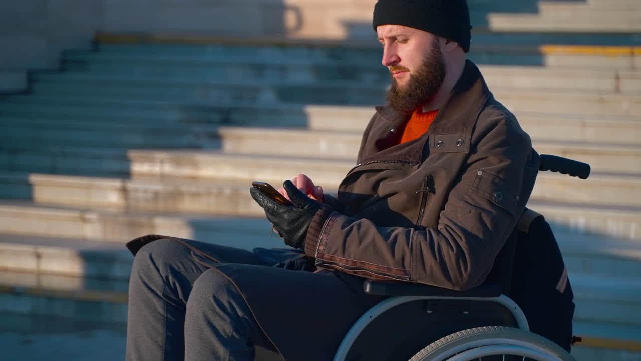 hombre en silla de ruedas usando un teléfono inteligente