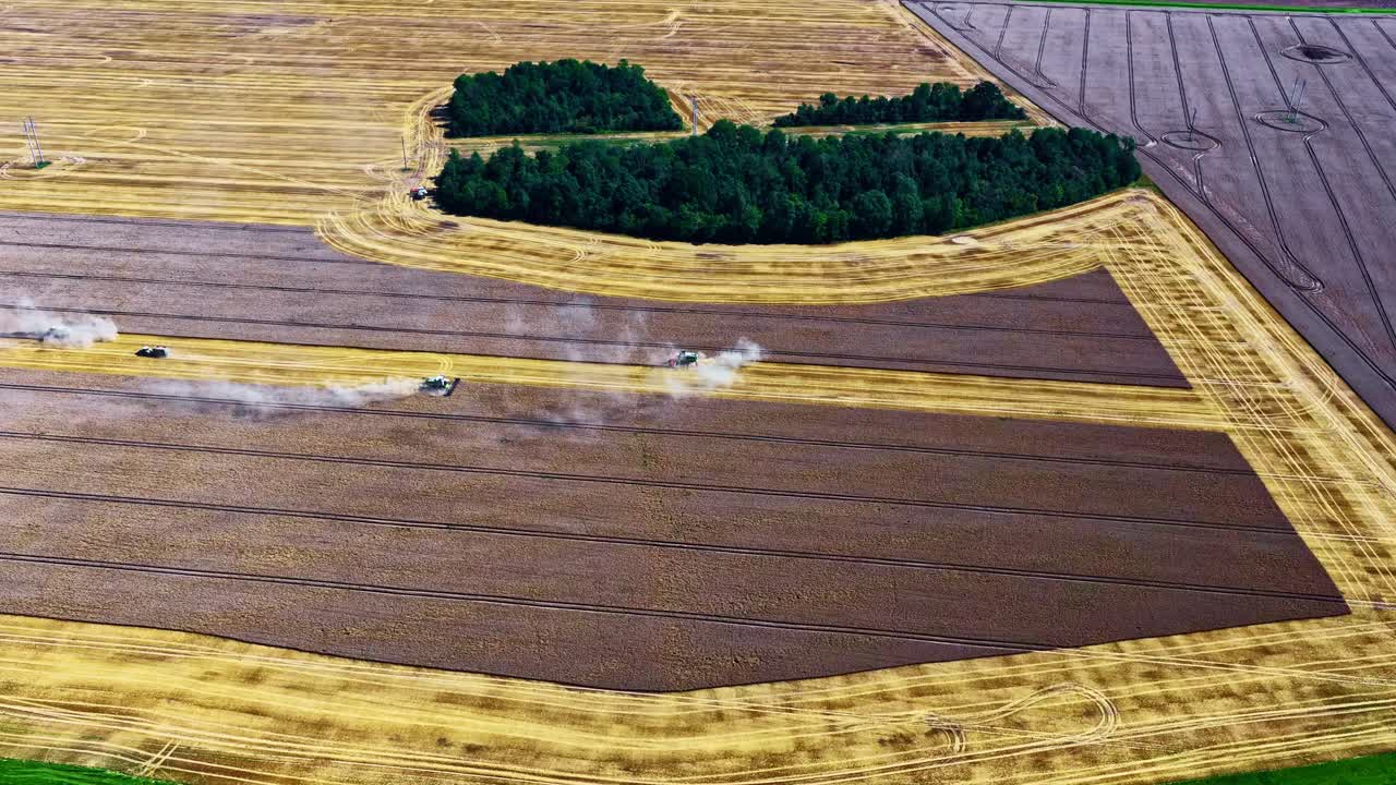 Multiple machines harvest crops in large fields, viewed from a high aerial perspective