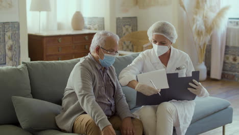 médico en ropa médica hablando con un anciano antes de la vacunación