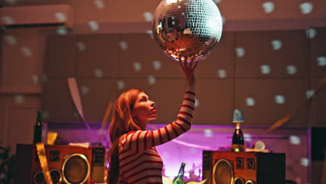 woman touching disco ball relaxing alone in room close up. girl holding beer