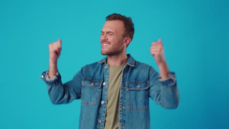 young man celebrating success on blue background