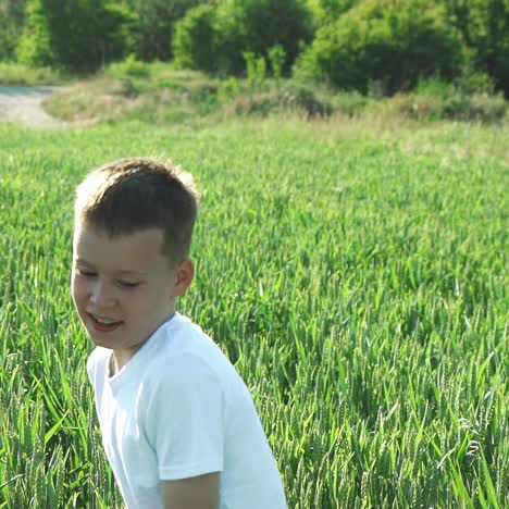 happy boy running in green wheat field. slow motion