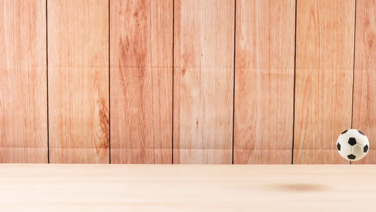 una pelota de fútbol rebotando en un piso de madera