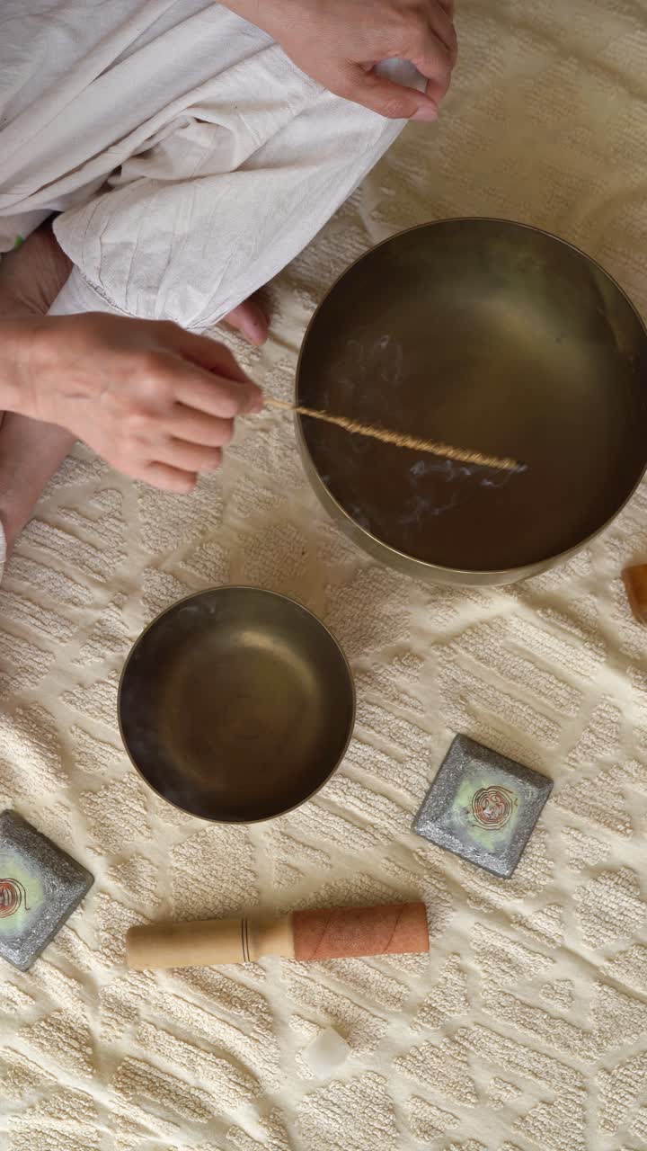 Vertical View Of A Person Holding An Incense Stick Over A Himalayan Singing Bowl. High Angle Shot