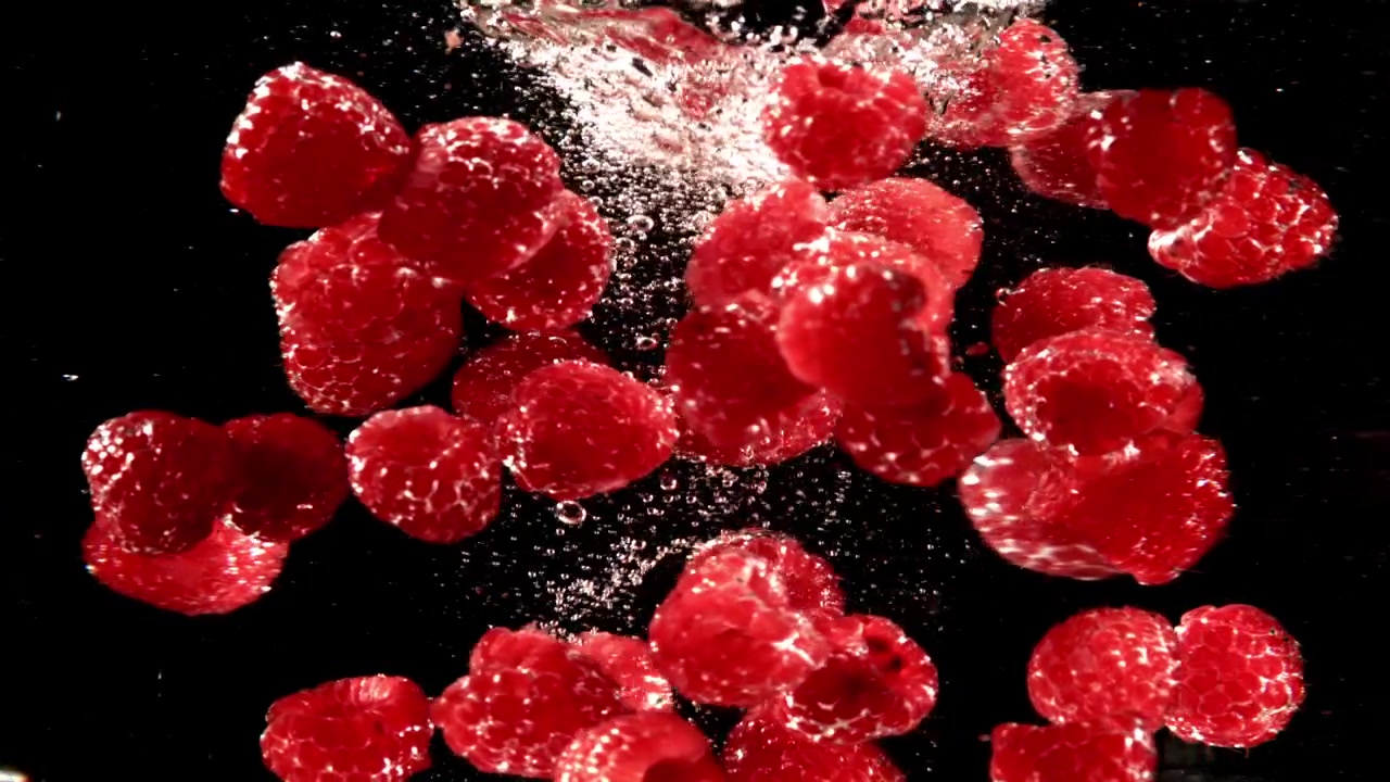 Slow Motion of Red Raspberries Falling and Splashing in Water