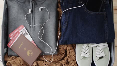 close up of suitcase with passport and packed clothes on wooden background