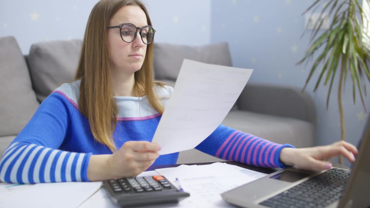 mujer usando calculadora para calcular facturas domésticas en el hogar, haciendo papeleo para pagar impuestos