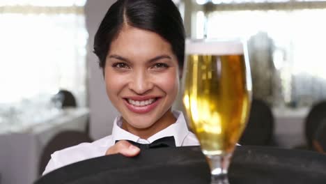 Pretty-waitress-holding-tray-with-glass-of-beer