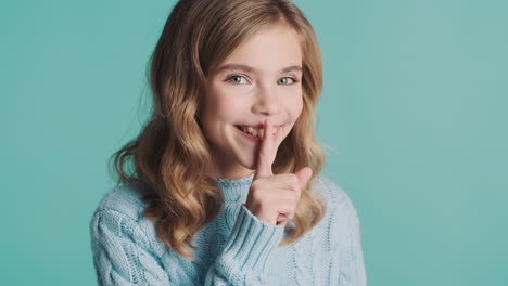 happy teenage caucasian girl making silence gesture in front of the camera.