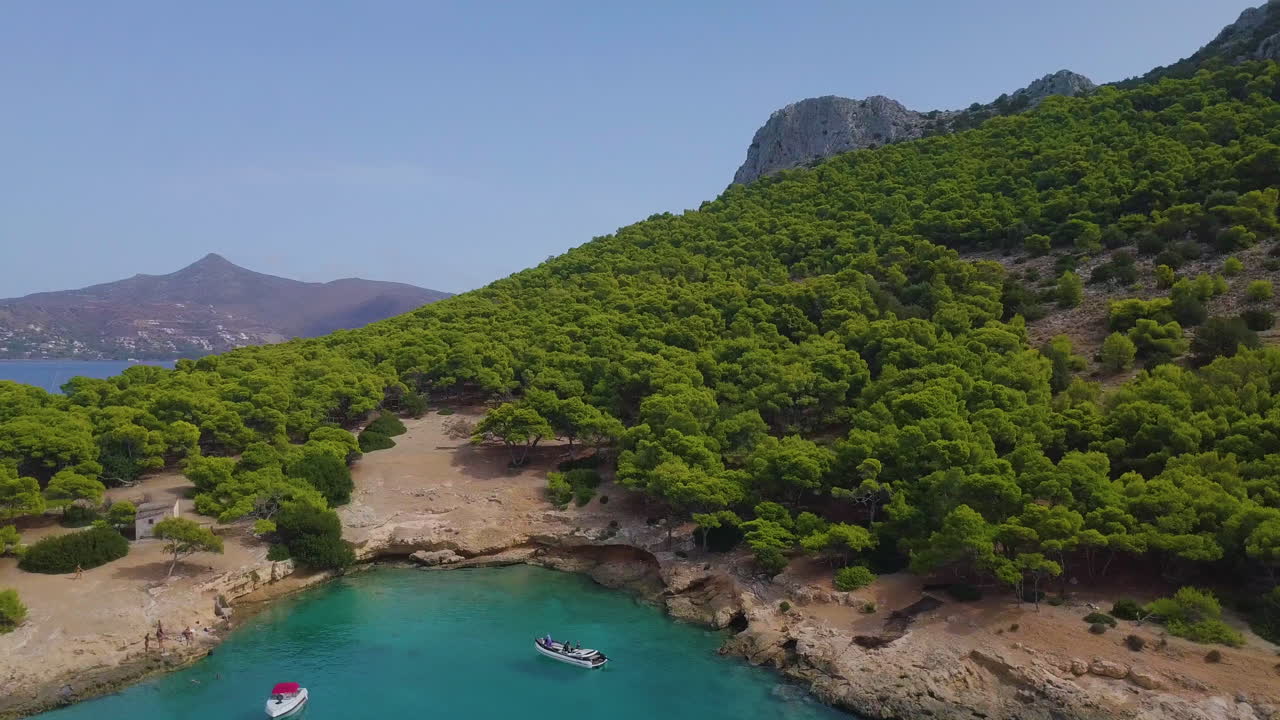Ascending drone shot of moored yachts and catamarans on a beautiful bay with many green trees