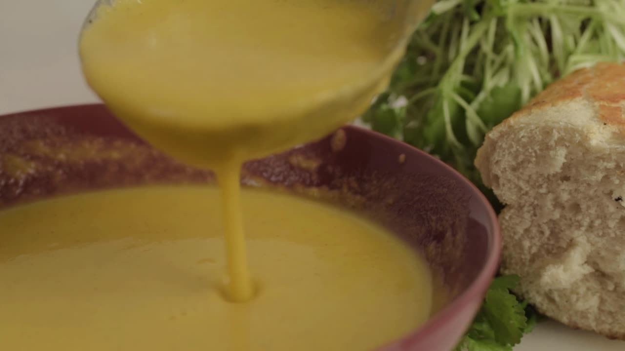 Serving carrot and coriander soup with ladle