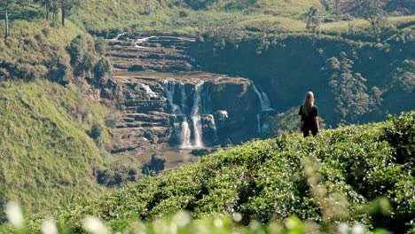 footage of a woman walking through lush tea plantations at saint clair’s falls in nuwara eliya, sri lanka.