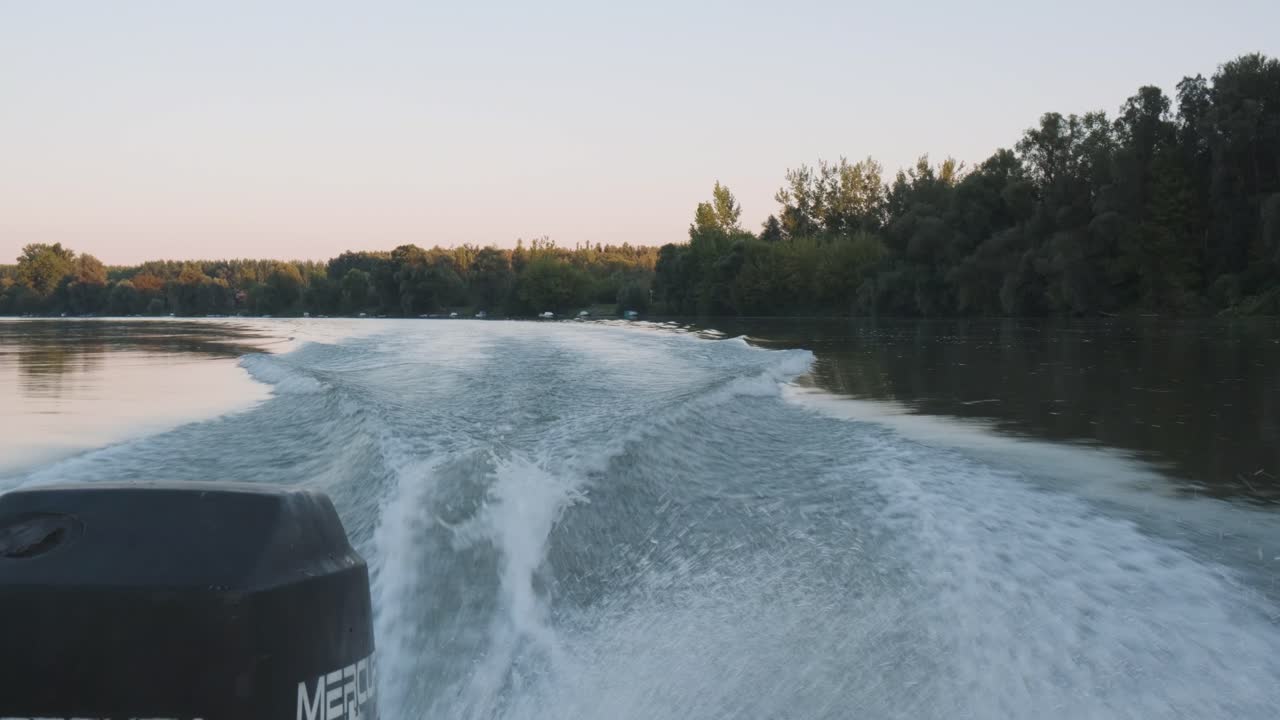 Shot from back of a boat showin the motor and the wake in the water