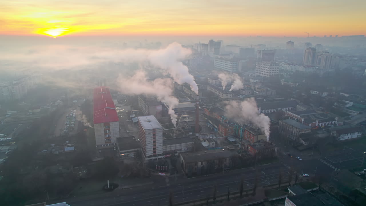 Aerial drone view of an production facility in Chisinau at sunrise, Moldova. Cityscape with multiple buildings, pipes with felling steam