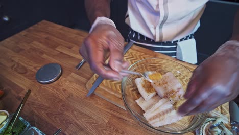 preparación de bacalao asado en una sartén por un chef caribeño