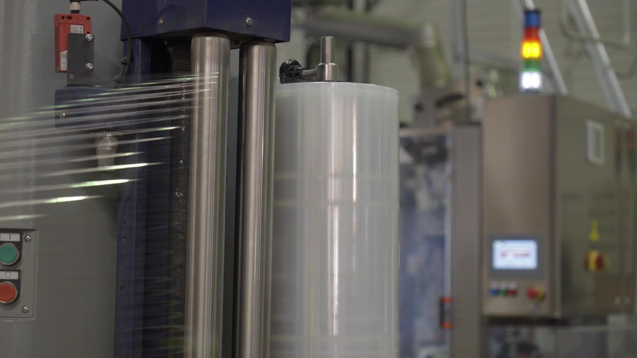 Industrial stretch wrapping machine rolls transparent film around a pallet