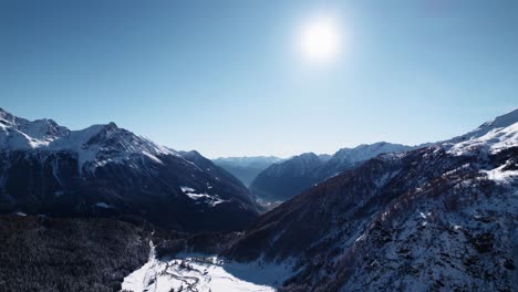 Aerial-view-of-snow-covered-mountain-landscape-with-forests-on-a-sunny-winter-day-in-Alp-Grum,-Switzerland